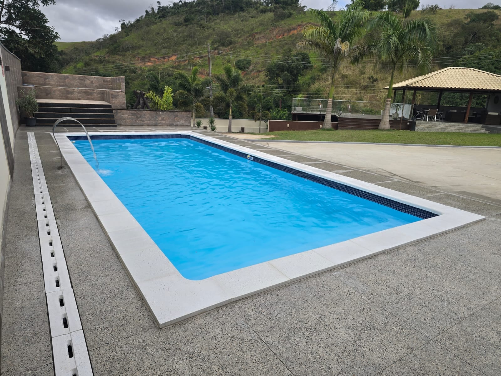 Piscina com cascata e as montanhas ao fundo